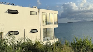 A modern building with large windows overlooking a body of water. - Ocean Front Property (Naguabo)