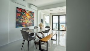A modern dining area with a glass table, black chairs, and a wooden bench. - Ocean Front Property (Naguabo)