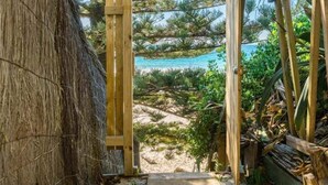 A wooden pathway leading to a beach with a thatched structure on the left. - Billabelongil - 40A Childe St, Byron Bay (Byron)