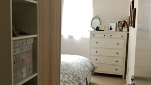 Un dormitorio con cama, cómoda y armario con contenedores de almacenamiento.