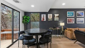 Une pièce moderne avec une table ronde et des chaises, un canapé, une petite table d’appoint et des tableaux encadrés au mur.
