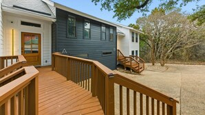 Une maison à deux étages dotée d’une terrasse en bois et d’un escalier menant à l’étage supérieur.