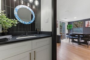 A modern bathroom with a black and white color scheme, a round mirror with a blue and white pattern, and a potted plant. - Spacious Retreat Near Downtown (Austin)