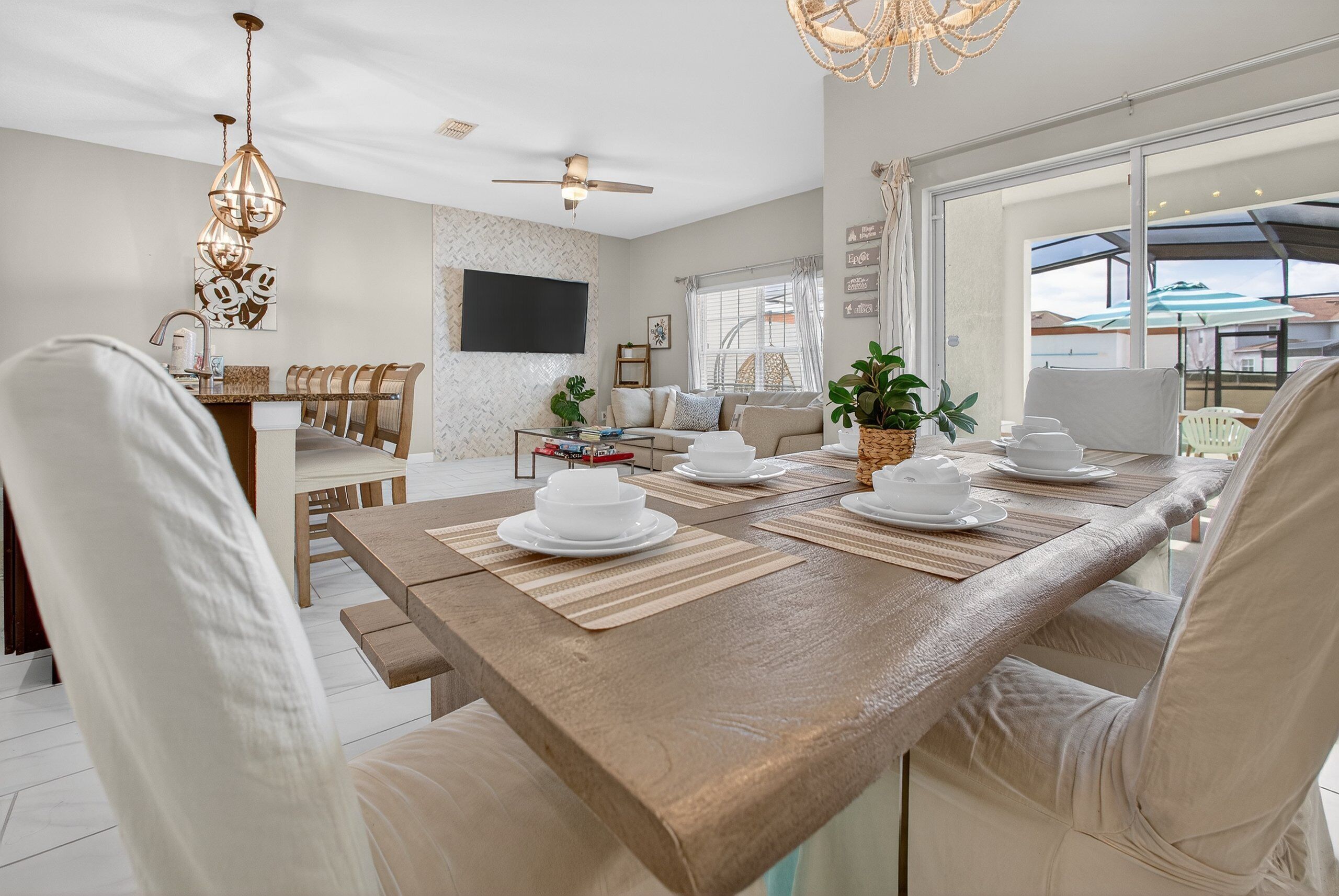 A spacious dining area with a long wooden table set for a meal, surrounded by cushioned chairs.