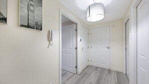 Un pasillo con una puerta y una pared blancos, y un aplique colgante.