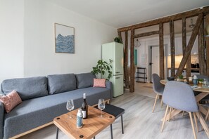 Un salon moderne avec un canapé gris, une table basse en bois et un coin repas comprenant une table et des chaises.