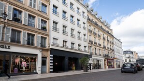 Vista de una calle con una hilera de edificios, incluyendo una tienda con maniquíes y un letrero que dice "GLF".