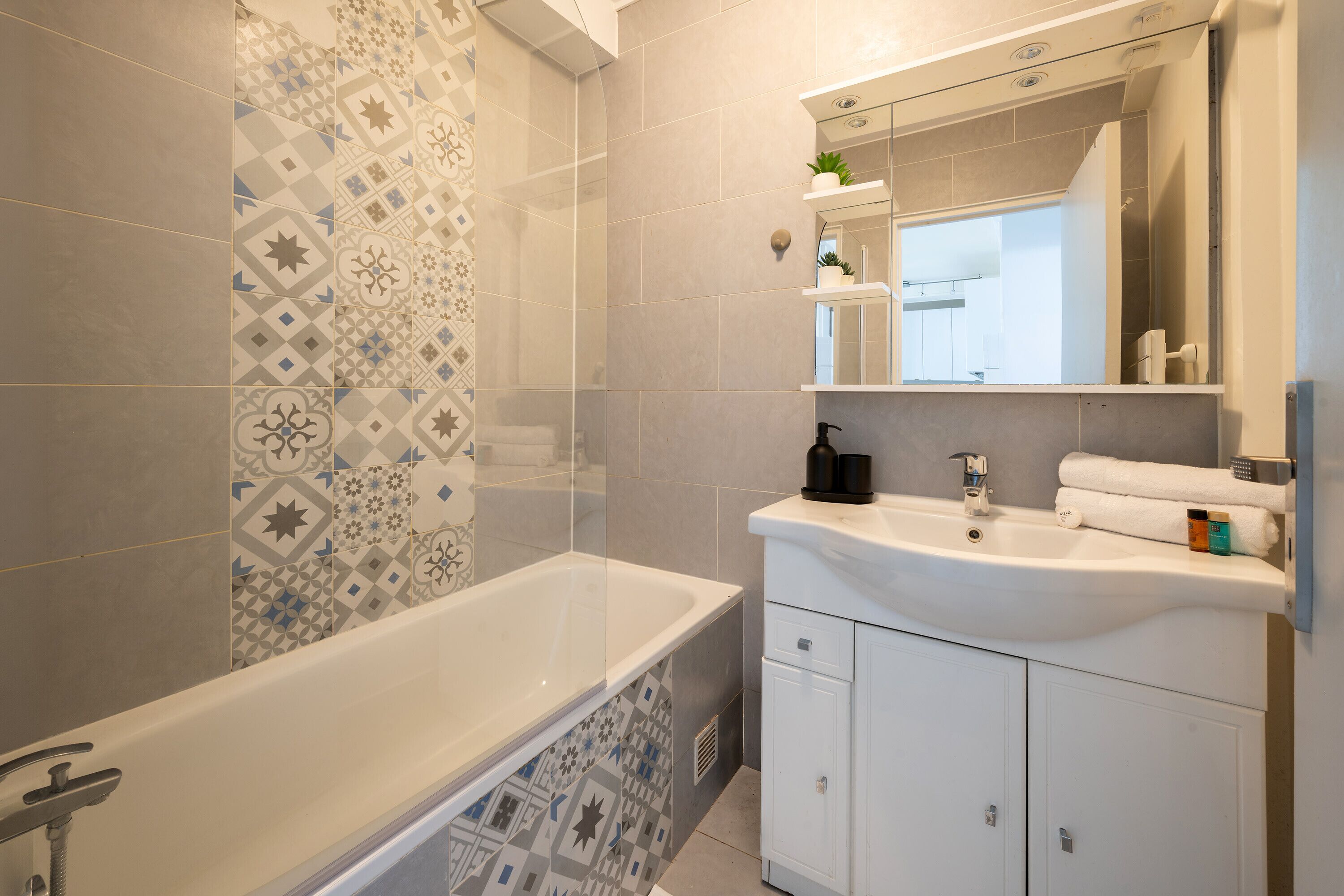 A modern bathroom with a bathtub, a sink, and a mirror.