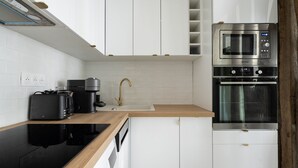 Una cocina moderna con armarios blancos, encimera negra, horno empotrado y microondas.