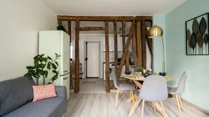 Una sala de estar moderna con un sofá gris, una mesa de comedor con sillas y una estructura de vigas de madera.