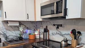Una cocina moderna con armarios blancos, horno de acero inoxidable, microondas y lavavajillas integrado.