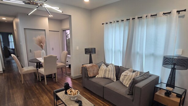 Una sala moderna con un sofá gris, una mesa de centro y una zona de comedor con sillas y una mesa.