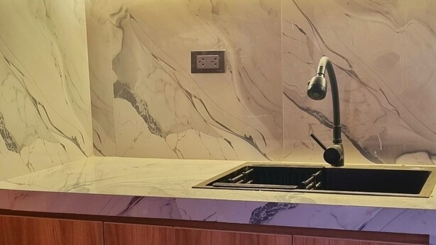 A kitchen with a marble backsplash, a built-in sink, and wooden cabinets. - Cusco Apartment, Prime Location (Cusco)