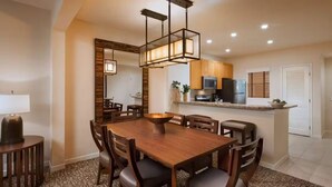 A dining area with a wooden table and chairs, a hanging light fixture, and a kitchen in the background. - COACHELLA LODGING!
Shuttle to Coachella next door, easy there and back! (Rancho Mirage)