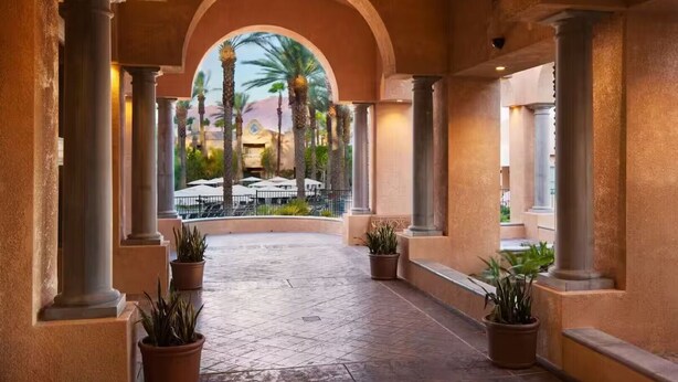 A covered walkway with columns, potted plants, and a view of outdoor seating and palm trees. - COACHELLA LODGING!
Shuttle to Coachella next door, easy there and back! (Rancho Mirage)
