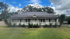 A two-story house with a front porch, surrounded by a well-maintained lawn and palm trees.