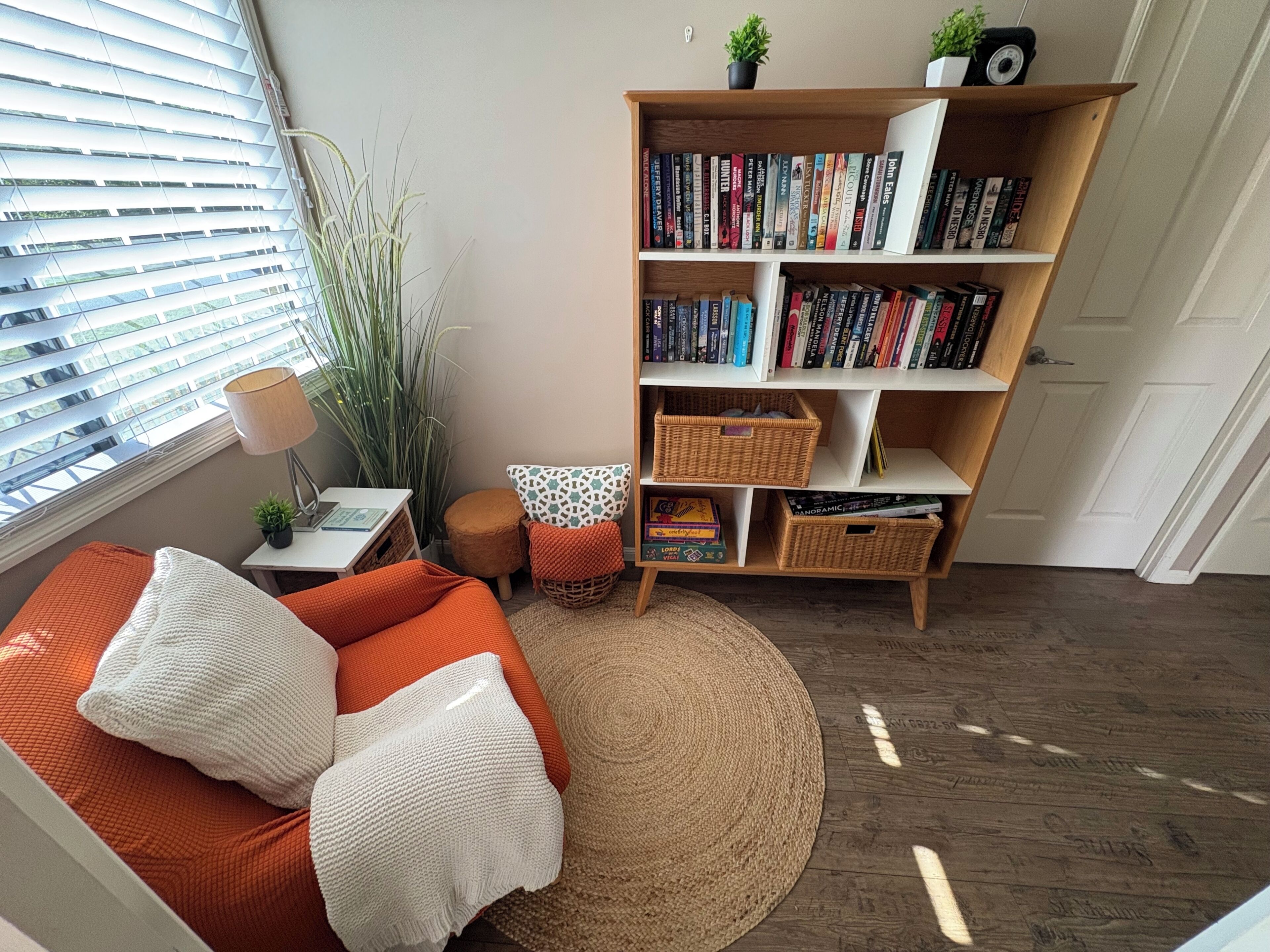 A cozy living room with a bookshelf, a sofa, a small table, and a potted plant.