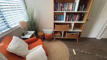 A cozy living room with a bookshelf, a sofa, a small table, and a potted plant.