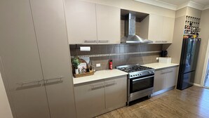 A modern kitchen with stainless steel appliances, wooden flooring, and built-in cabinetry.