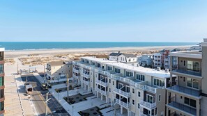 Ein Hotel direkt am Strand mit mehrstöckigen Gebäuden, Balkonen und Blick auf den Strand und das Meer.