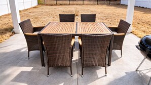 Un patio al aire libre con una mesa de madera y seis sillas de mimbre.