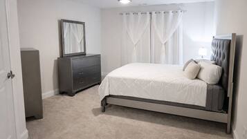 A bedroom with a bed, a dresser, a mirror, and a ceiling fan.