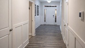 A hallway with white walls, wooden flooring, and a door at the end.