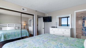 A bedroom with two beds, a TV, a dresser, and a window with a view. - Seawinds 702 (North Myrtle Beach)