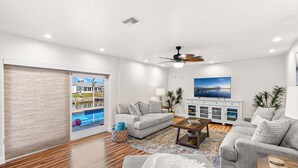 A living room with a sofa, coffee table, and a view of a swimming pool. - Merritt Island Waterfront Oasis W/ Private Pool, Spa-like Hot Tub & Boating Dock! 🌅 (Merritt Island)