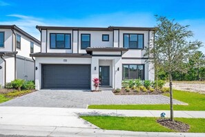 A modern two-story house with a garage, a well-maintained lawn, and a small tree in the front yard. - 1209-9-b -mansion Themed With Pool Near Disney (Davenport)