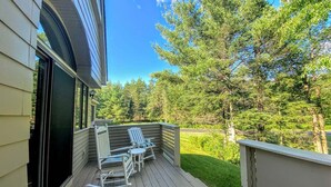 A wooden deck with two rocking chairs and a table, overlooking a well-maintained lawn and trees. - Fv49 Wow Stunning Single Level Home Next to Golf Course and Mt Washington Hotel (Bretton Woods)