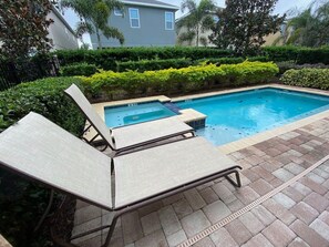Ein Schwimmbad mit Liegestühlen und einer Pflasterterrasse.