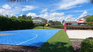 A basketball court with a blue surface, surrounded by green grass and a sandy area. - 480-7-ld-large Luxury (Kissimmee)