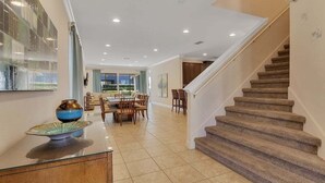 A spacious living area with a dining table, chairs, and a staircase leading to another level. - 480-7-ld-large Luxury (Kissimmee)