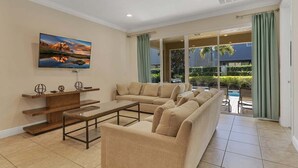 A spacious living room with a large sofa, a coffee table, and a flat-screen TV mounted on the wall. - 480-7-ld-large Luxury (Kissimmee)