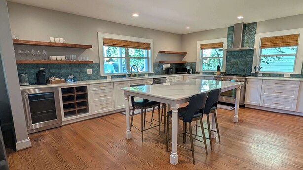 A modern kitchen with a central island, wooden flooring, and large windows. - Stylish Durham Retreat - Walkable, Sleeps 6 (Durham)