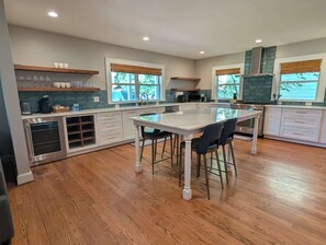 A modern kitchen with a central island, wooden flooring, and large windows. - Stylish Durham Retreat - Walkable, Sleeps 6 (Durham)