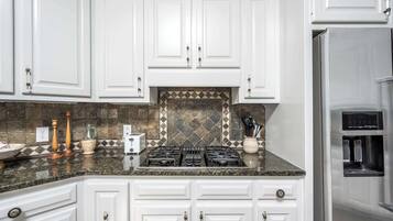 Una cocina con alacenas blancas, estufa a gas, tostadora y refrigerador de acero inoxidable.