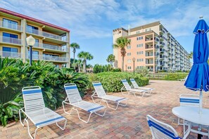 A hotel courtyard with lounge chairs and a table, surrounded by greenery and buildings. - 405 Atlantis (Fernandina Beach)