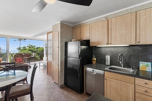 Una cocina con armarios de madera, un refrigerador negro, lavavajillas y un fregadero.