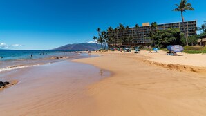 A beach with a hotel in the background, palm trees, and clear skies. - Mana Kai 314 (Kihei)