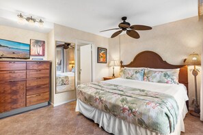Un dormitorio con cama, cómoda, ventilador de techo y mesita de noche con lámpara.