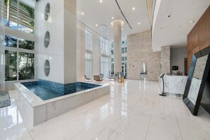 A spacious lobby with a large indoor pool, modern furniture, and a reception desk. - Brickell River Views- Modern Amenities in the City (Miami)