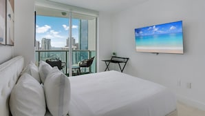 Une chambre d’hôtel moderne, dotée d’un grand lit, d’un bureau et offrant une vue sur le paysage urbain grâce à une grande fenêtre.