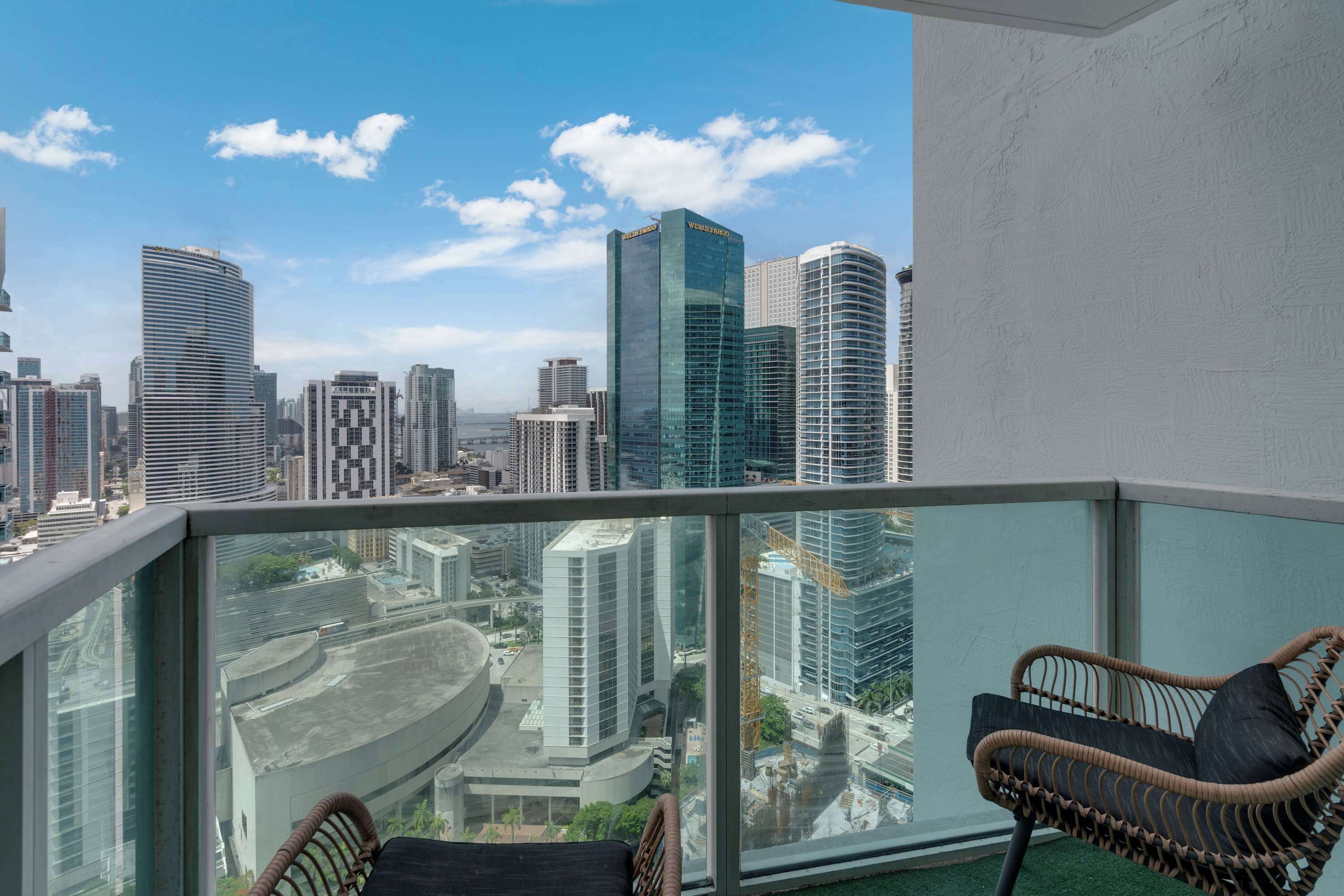 A balcony with a view of a cityscape, including modern buildings and a construction crane.