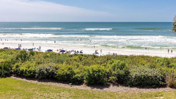 A beach with people, umbrellas, and a clear sky.