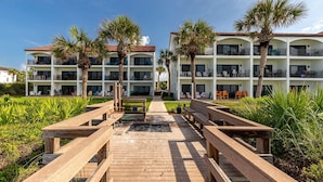 A resort with multiple-story buildings, outdoor seating, and palm trees.
