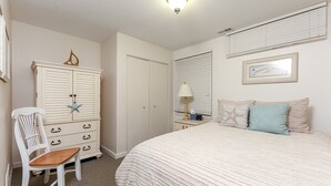 A bedroom with a bed, a dresser, a chair, a nightstand, and a wall-mounted lamp. - Beautiful 2 Bedroom Lakeside Condo at The Shores 5677 (Williamsburg)