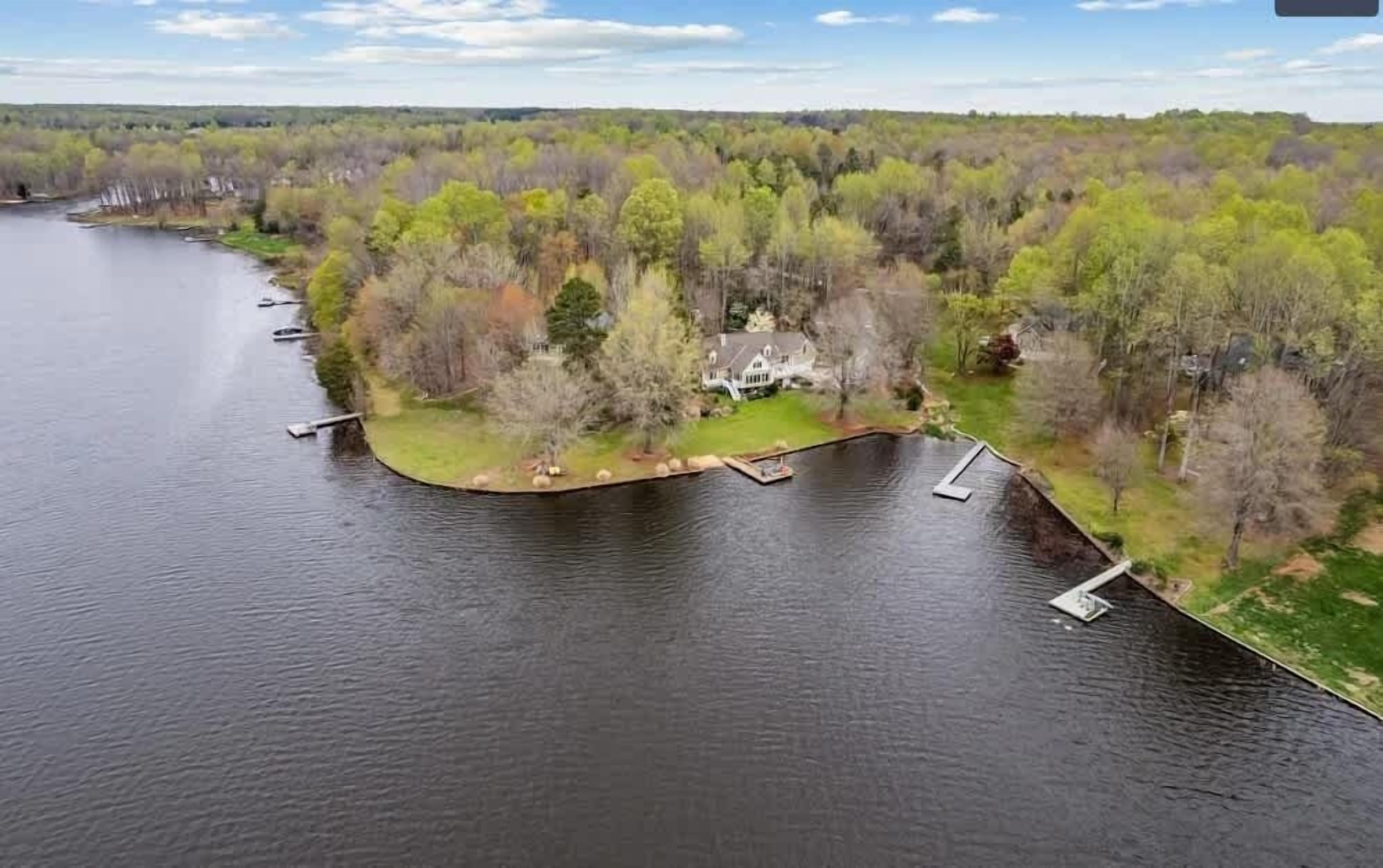 Una propiedad junto al lago con muelle, casa y bosque circundante.