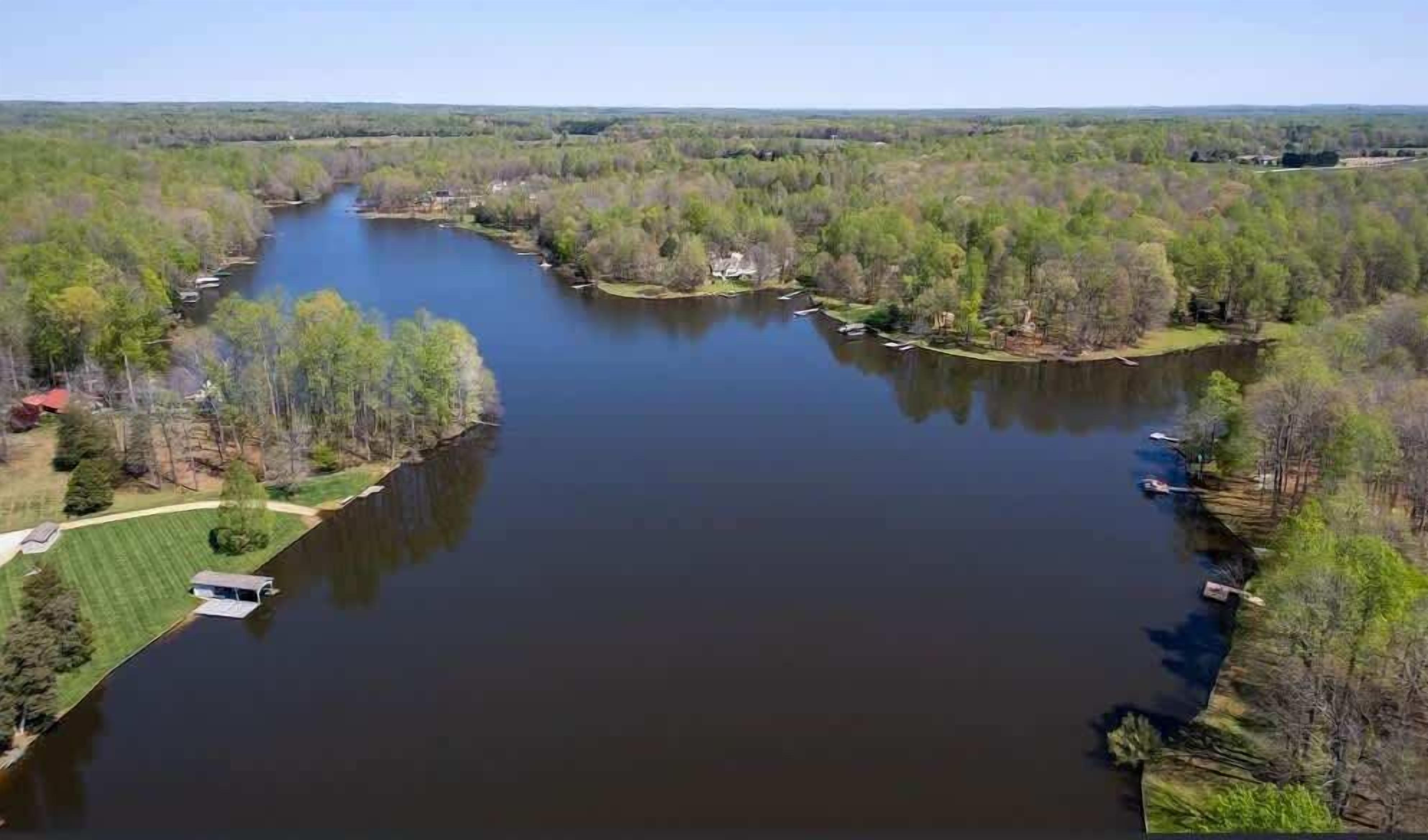 A river with a boat dock, surrounded by trees and a grassy area.